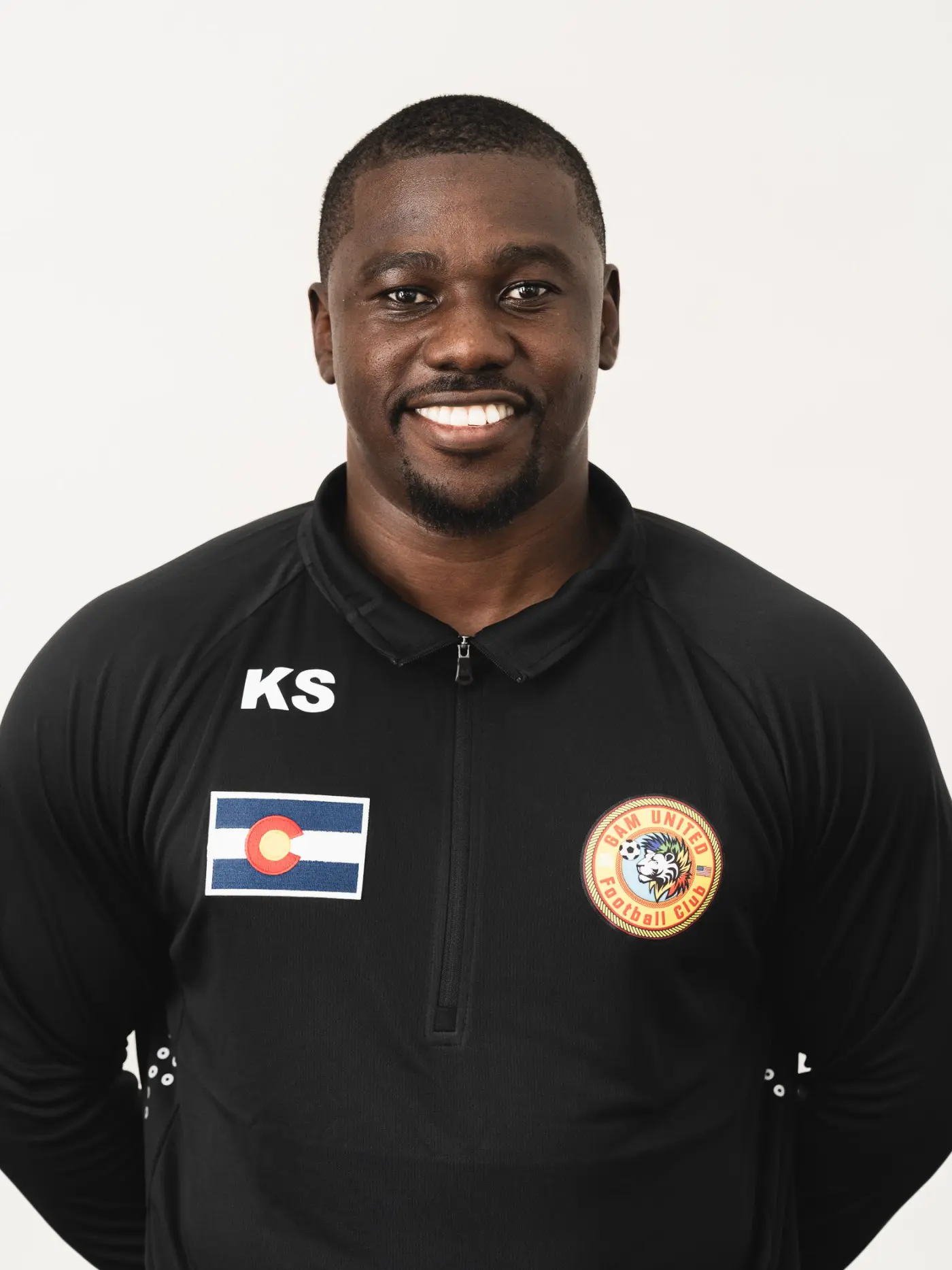 Smiling man wearing a black team jacket