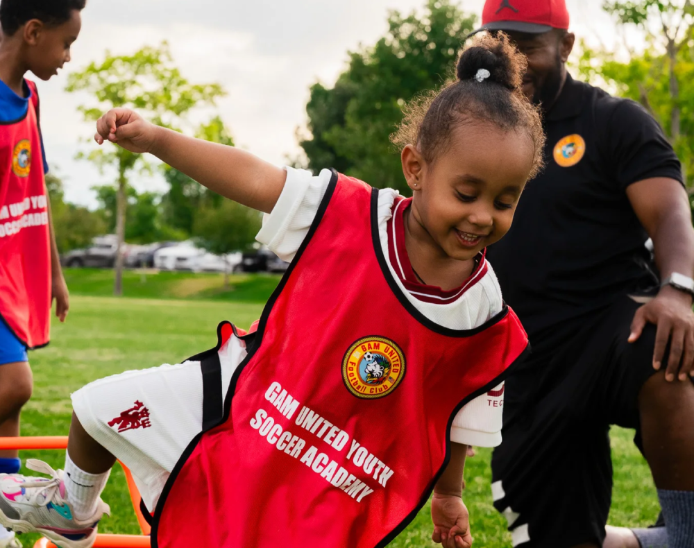 Child playing soccer in red jersey
