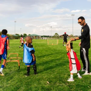 Kids playing soccer with their coach